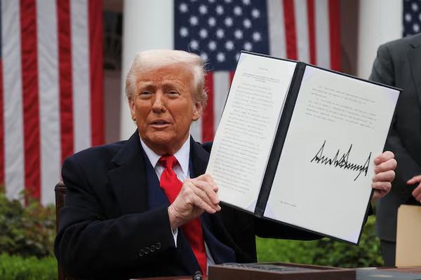 U.S. President Donald Trump holds a signed executive order on tariffs
